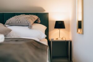 łóżko i stolik nocny z czarną lampką